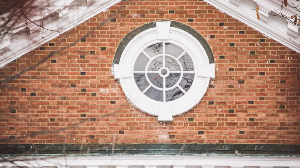 Round white window surrounded by brick